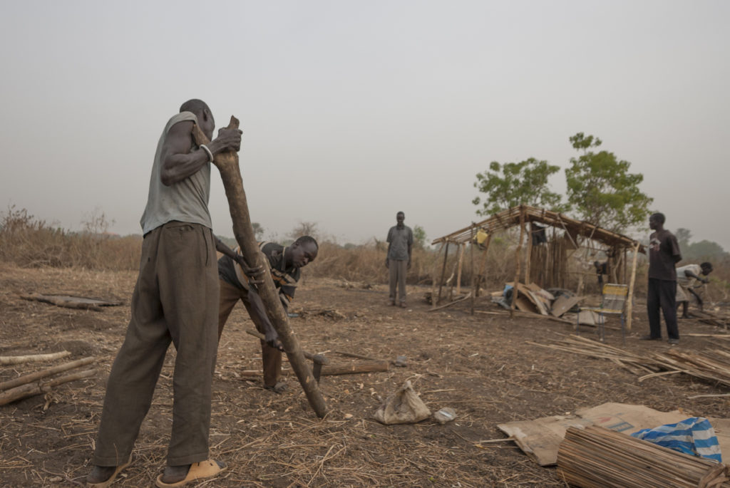Réfugiés préparent le bois pour une construction de cabane dans le camp de personnes déplacées. Photo : Vlad Karavaev.