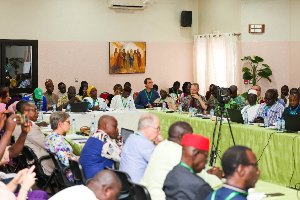 Une salle de réunion avec une série de personnes attablées venant d'Afrique et d'Europe