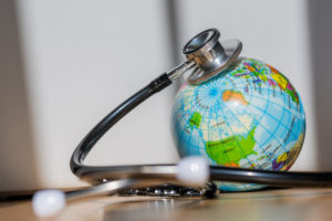Symbole de la couverture sanitaire universelle : un stéthoscope enroulé autour d'un globe, symbolisant l'unité médicale mondiale et le système international de soutien aux soins de santé