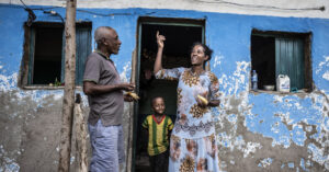 Une femme et son enfant avec un homme en Afrique parlant devant une maison